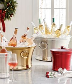 several different types of wine in buckets and glasses on a table next to a christmas tree