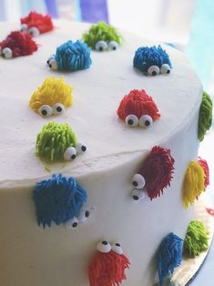 a white cake decorated with colorful frosting and monster eyes on it's side