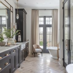 an elegant bathroom with marble counter tops and wood flooring, along with large windows