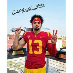 a man in a football uniform holding a trophy and making the peace sign with his hands