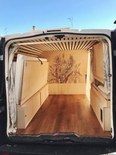 the back end of a van with wood flooring and painted mural on it's side