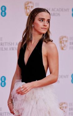 a woman in a black and white dress posing for the camera at an awards event