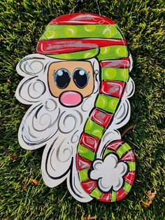 a christmas ornament hanging on the grass with a santa clause hat and candy cane