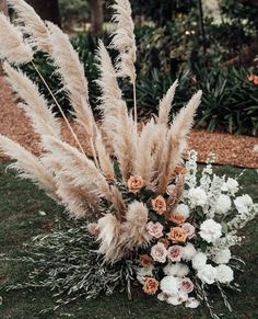 an arrangement of flowers and grasses in the grass