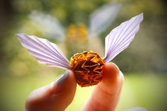 a hand holding an origami piece in the palm of it's left hand