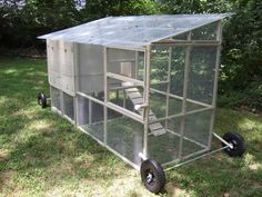 a small chicken coop on wheels in the grass