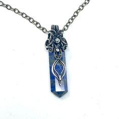 This pendant is handmade using fine silver wire wrapped around a Lapis Lazuli gemstone point. It hangs from an oval chain which closes with a hook clasp. The chain is 24 inches long ( 61 cm), the pendant is 6 cm long (2.4 inches) and 0.5 inches wide.It has been tarnished and polished to create an antique finish. Wire Wrapped Amulet Pendant Crystal Necklace, Wire Wrapped Amulet Crystal Pendant Necklace, Artisan Wire Wrapped Pendant Crystal Necklaces, Artisan Wire Wrapped Crystal Pendant Necklaces, Artisan Wire Wrapped Crystal Pendant Necklace, Unique Sterling Silver Nickel-free Crystal Necklaces, Spiritual Silver Crystal Necklace With Lobster Clasp, Spiritual Wire-wrapped Metal Crystal Necklace, Hand Wrapped Sterling Silver Spiritual Necklace