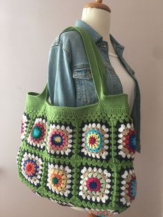 a green crocheted bag on a mannequin head with a denim jacket