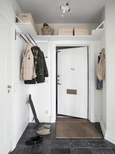 an entryway with clothes and shoes hanging on the wall, next to a door