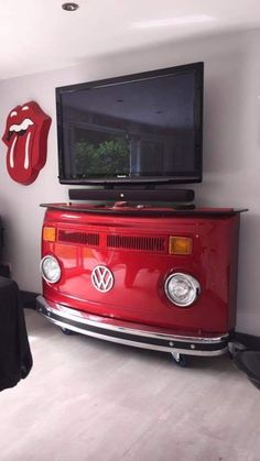 a red vw bus sitting in front of a tv on top of a dresser