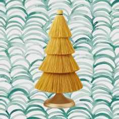 a small yellow christmas tree sitting on top of a wooden stand in front of blue and white waves