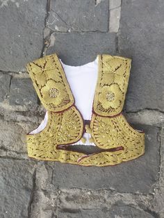 This is an all handmade vintage vest, hand embroidered with gold thread (also known as 'srma' or Ottoman name 'sirma'.) It was made by the Ottoman patterns and style of embroidery left on the Balkans as a cultural inheritance of their five century ruling at the Balkans.  The vest was made in the 1960's or the 1970's and it is kept in an excellent condition, without damages of any kind. The vest is girl size, for the age between 10-12 years old, with a chest circumference of 65 cm (25.6 inches). Festive Vest With Multicolor Embroidery, Festive Embroidered Vest With Multicolor Embroidery, Festive Embroidered Multicolored Vest, Traditional Festive Vest With Intricate Embroidery, Traditional Fitted Gold Embroidered Fabric, Festive Fitted Embroidered Habesha Kemis, Festive Fitted Habesha Kemis With Embroidery, Fitted Embroidered Habesha Kemis For Festive Occasions, Gold Traditional Wear With Embroidered Border For Ceremonies