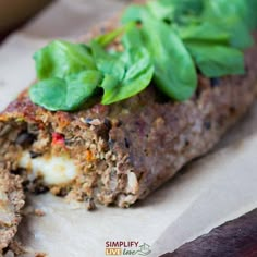 a meatloaf with spinach leaves on top is cut in half and ready to be eaten