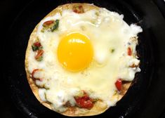 an egg is sitting on top of a pizza in a skillet with cheese and tomatoes