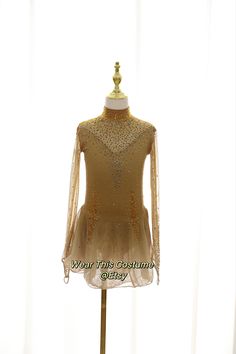 a mannequin wearing a gold dress with sheer sleeves