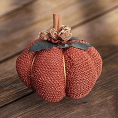 a red knitted pumpkin sitting on top of a wooden table