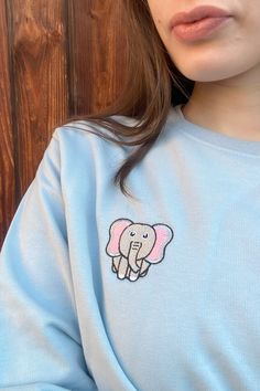 Add a touch of majestic charm to your wardrobe with our Elephant Embroidered Crewneck Sweatshirt. Made from a soft cotton blend, this relaxed fit pullover features a beautiful elephant embroidery, capturing the essence of elegant and unique style. The unisex design makes it perfect for everyone, offering a stylish and comfortable option for any casual occasion. Whether you're lounging at home or heading out, this sweatshirt brings warmth and majestic flair to your look. Cute Long Sleeve T-shirt With Embroidered Text, Cute Loungewear Tops With Ribbed Cuffs, Cute Ribbed Cuffs Tops For Loungewear, Cute Tops For Loungewear With Ribbed Cuffs, Cute Relaxed Fit Tops With Ribbed Cuffs, Cute Tops With Ribbed Cuffs For Loungewear, Casual Embroidered Loungewear T-shirt, Casual Embroidered T-shirt For Loungewear, Cute Crew Neck Top With Ribbed Cuffs