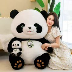 a woman sitting next to a giant panda bear