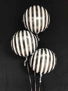 three black and white striped balloons with tassels