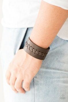 a person wearing a brown bracelet with an arrow design on it's wrist and holding onto his jeans