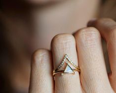 a woman's hand with a gold and diamond ring on her finger, showing the triangle shaped stone