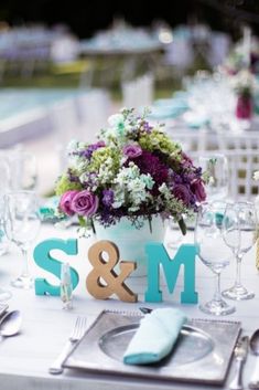 the table is set with silverware and purple flowers in a blue vase that says s & m