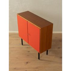 an orange cabinet sitting on top of a wooden floor