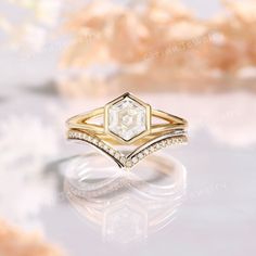 a diamond ring on a white surface with some flowers in the backgrouf