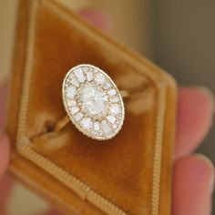 an antique diamond ring is being held in a velvet box with gold trimmings