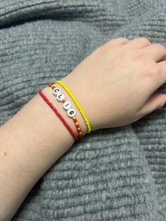 a woman's hand wearing two bracelets with letters on each wrist and the word love spelled in small beads