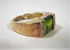 Wide gilt silver band with square green stone, silver sections on each side with what appear to be diamond chips. Measures slightly under a size 6 (between 5 3/4 and 6 on ring sizer).The stone is a yellowish green, possibly a peridot, but could be a synthetic stone.  It is signed 925 with an initial on one side of the interior band, and China on the other side.Some light tarnish visible, several of the small chips on the side are missing (so small a loup is necessary to see them).The stone has a Vintage Green Rings With Accent Stones, Green Rectangular Stone Jewelry For Formal Occasions, Formal Green Jewelry With Rectangular Stone, Formal Green Emerald Ring With Stone Setting, Vintage Green Emerald Ring With Diamond Accents, Green Rings With Diamond Accents For Formal Occasions, Formal Green Rings With Diamond Accents, Green Diamond Jewelry With Rectangular Stone, Green Square Cut Rings With Accent Stones