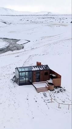 an aerial view of a house in the middle of snow covered ground with stairs leading up to it