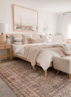 a bedroom with a bed, ottoman and rug on the floor in front of a window