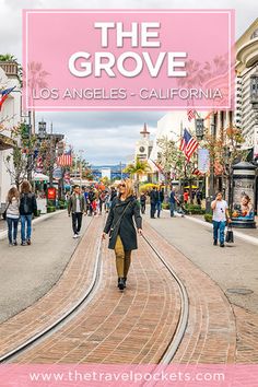 a woman walking down the street in front of a pink sign that says the grove los angeles