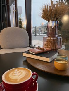 a cup of coffee sitting on top of a table next to a vase with flowers