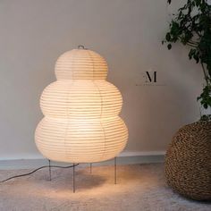 a white lamp sitting on top of a table next to a potted plant