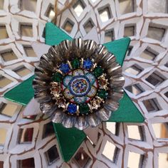 an intricately designed brooch is shown in the middle of a mosaic tile pattern