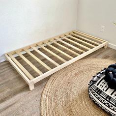 a bed frame sitting on top of a wooden floor next to a rug and potted plant