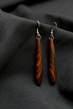 two wooden earrings sitting on top of a black cloth