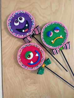 three decorated lollipops sitting on top of a wooden table