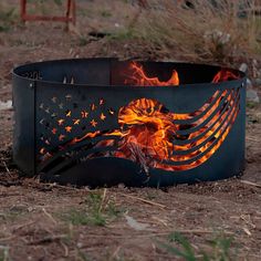 a fire pit with an eagle and american flag painted on the side, surrounded by dry grass