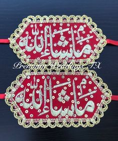 two red and gold embroidered tags with arabic writing on them sitting on a black surface