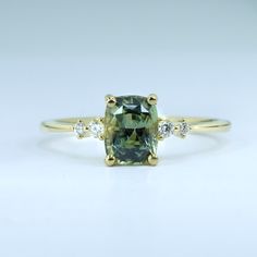 a green diamond ring with three diamonds on the band and one stone in the middle