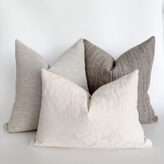 three pillows are stacked on top of each other, one is white and the other is gray