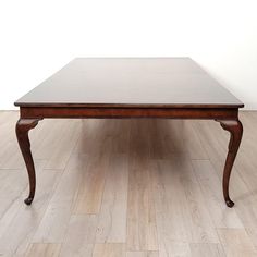 a wooden table sitting on top of a hard wood floor next to a white wall