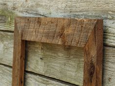 an old wooden frame hanging on the side of a wood wall with nails in it