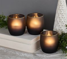 three black candle holders sitting on top of a book