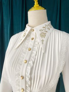 An embroidered blouse that looks like an aristocratic lady from medieval Europe. A cross and a rose are embroidered on the collar with gold thread (white) and silver thread (gray), and ivy is also embroidered on the cuffs. The back is decorated with lacework, and the chest is decorated with frills, pleats, and lace embroidery. For a young lady with a gorgeous atmosphere. 
 
 

 

 
 
 
 Color 
 
 White 
 Gray 
 
 
 Size 
 
 
 S size 
 
 Length: 60cm 
 Shoulder width: 37cm 
 Bust: 86cm 
 Waist: 7 Elegant Embroidered Bishop Sleeve Tops, Elegant Long Sleeve Embroidered Blouse, Fitted Elegant Blouse With Floral Embroidery, Elegant Blouse With Floral Embroidery And Bishop Sleeves, Elegant Embroidered Blouse With Peter Pan Collar, Formal Fall Blouse With Floral Embroidery, Fitted Blouse With Intricate Embroidery For Fall, Fitted Blouse With Peter Pan Collar And Embroidery, Fitted Embroidered Blouse With Peter Pan Collar