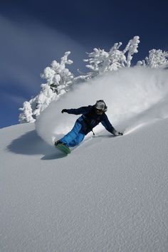 a man riding skis down the side of a snow covered slope with trees in the background