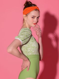 a woman in a green and white leotard with an orange headband